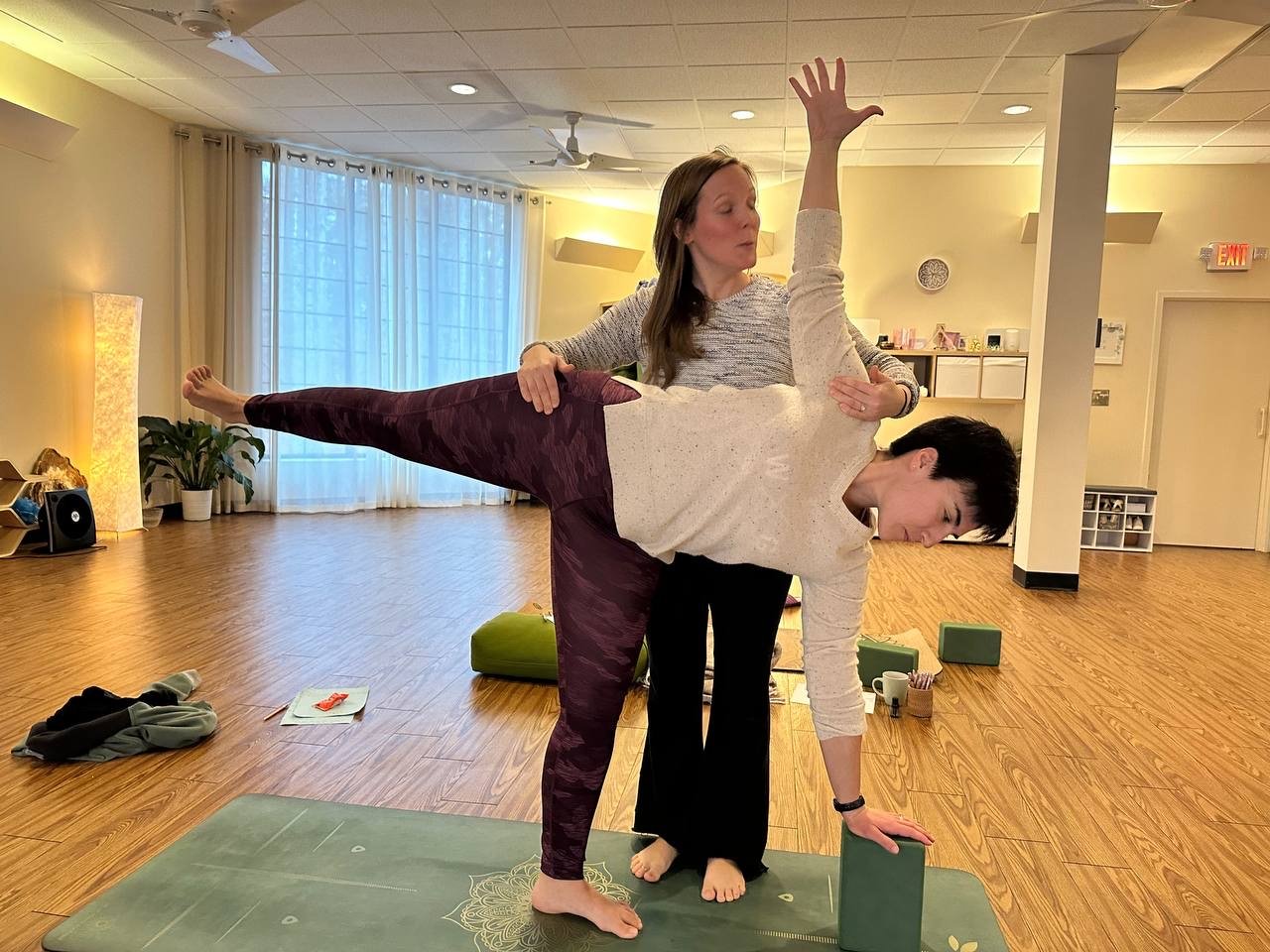 Megan Freeman giving a hands-on assist in half moon pose